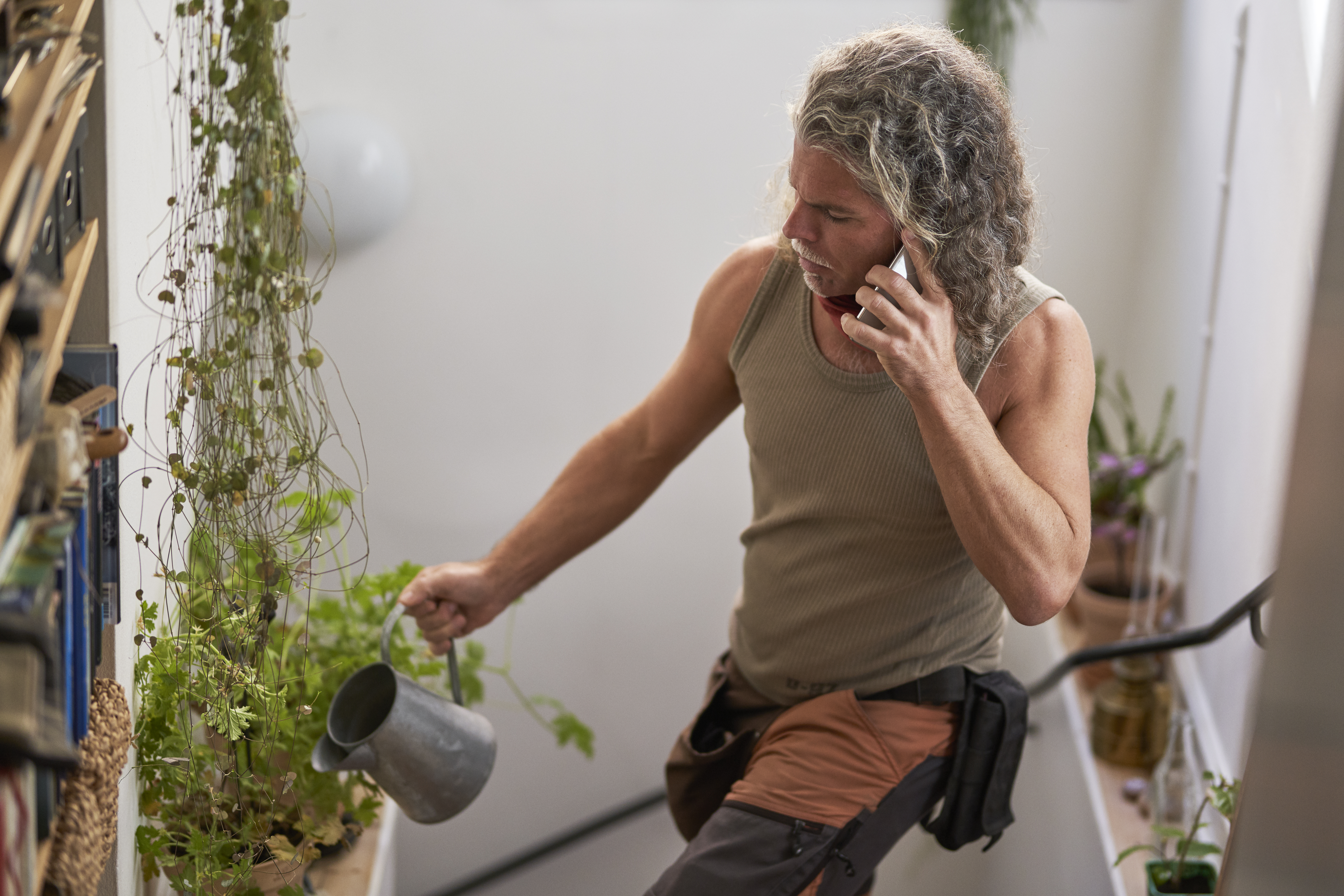 Mann vanner planter mens han snakker i telefon
