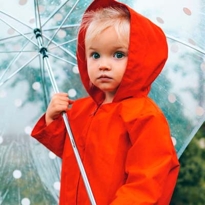 Ungt barn med paraply og rød regnfrakk
