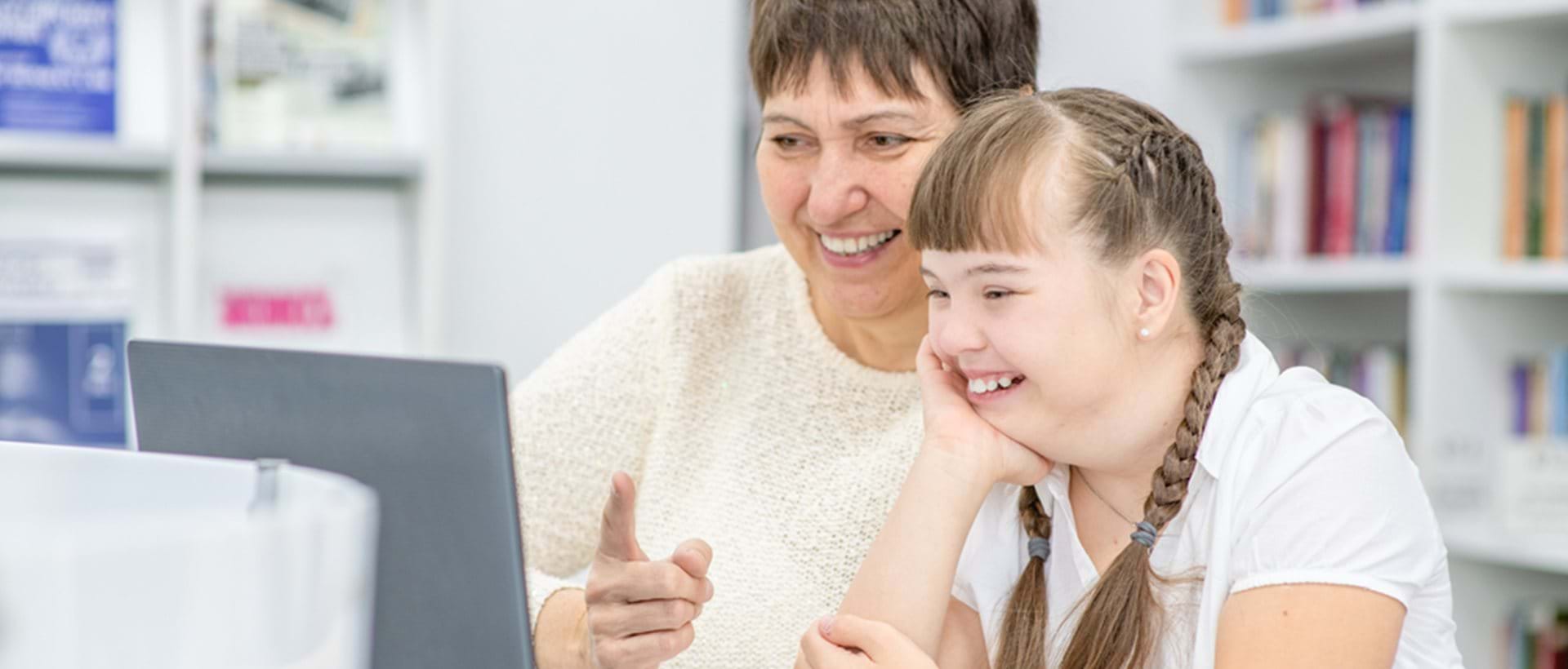 En voksen og et barn sitter ved en datamaskin sammen