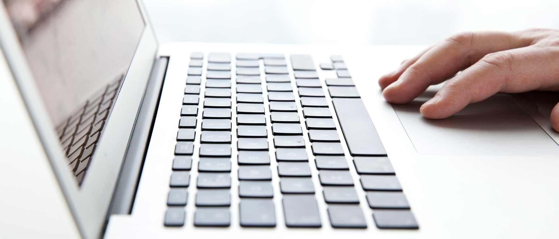 En person taster på tastaturet på sin bærbare datamaskin, og arbeider med med digital arkivering godkjent av Noark 5-standarden.
