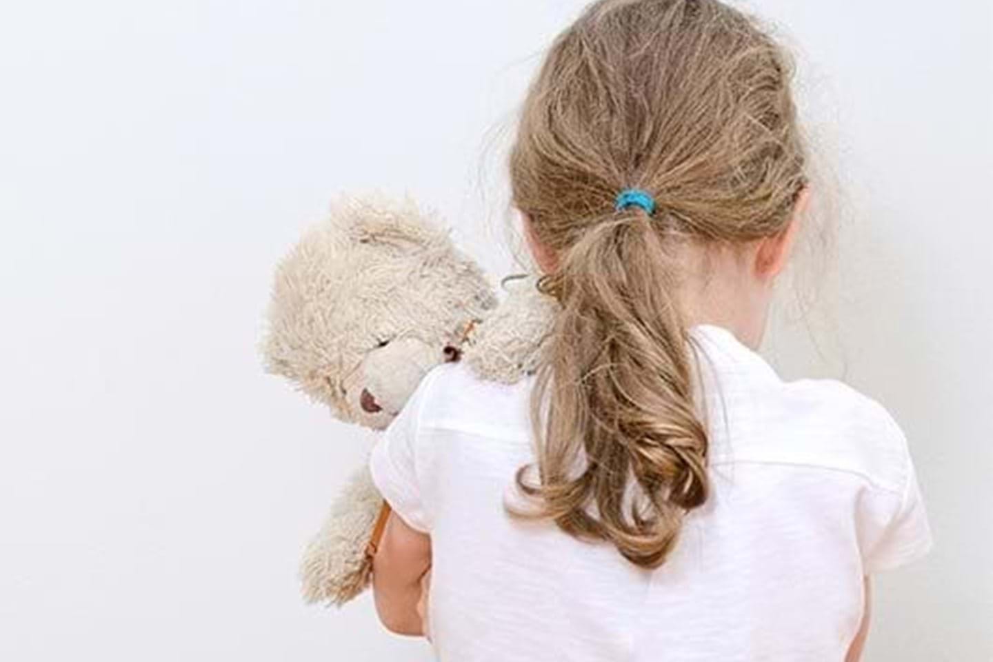 Barnevernvakt tilrettelegger sikker kommunikasjonen fra vakt til barnevern om barn i krise. Bildet viser en ung jente står med ryggen til kameraet og holder en bamse over skulderen sin.