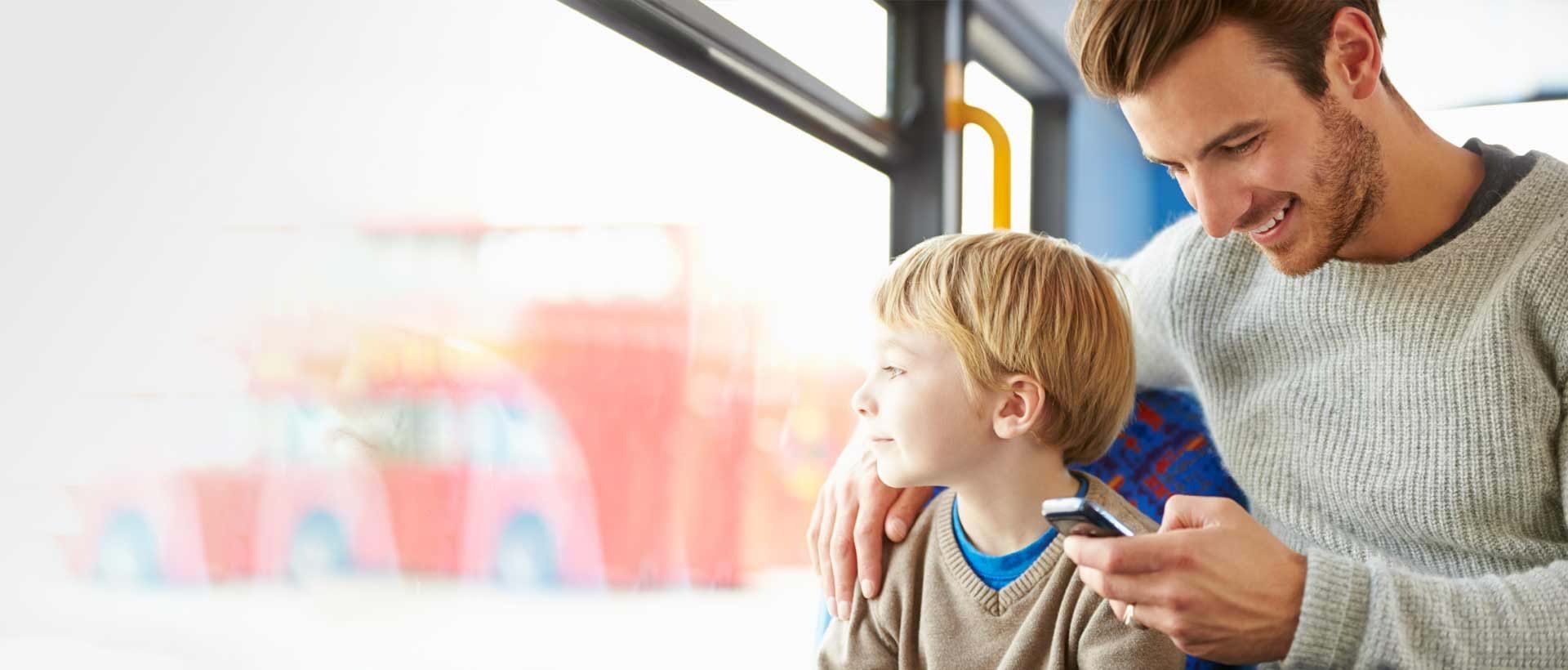 En mann og et barn sjekker dagens lekser på skole-appen mens de sitter på en buss.