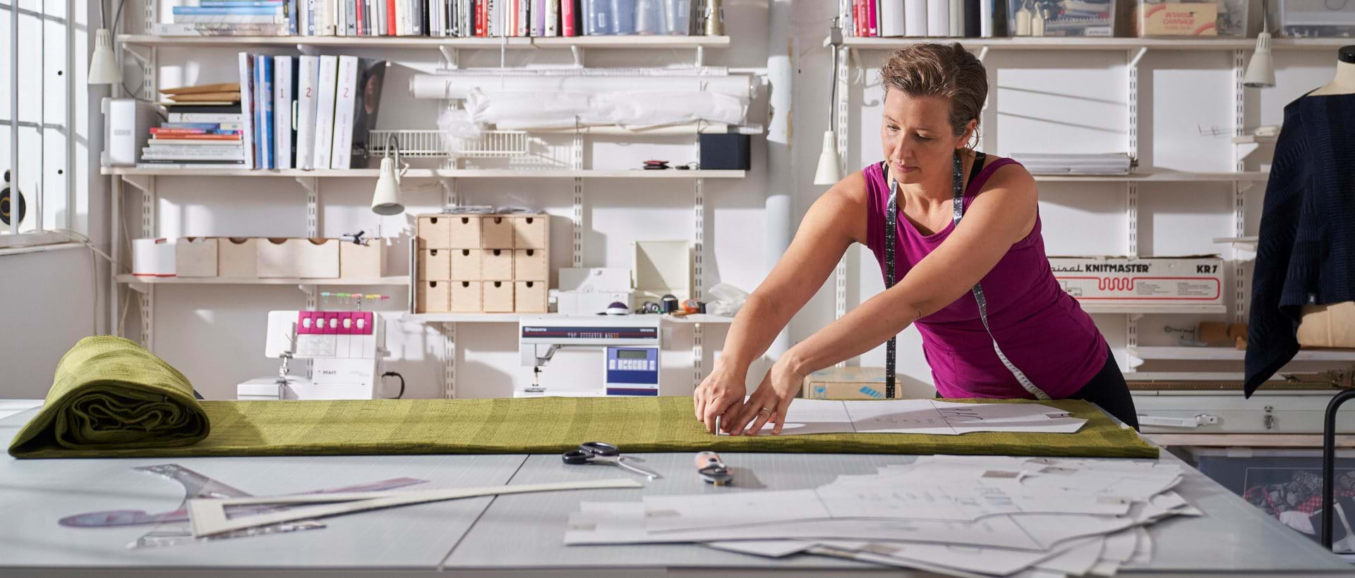 Butikkeier måler opp stoff til produksjon av nye klær