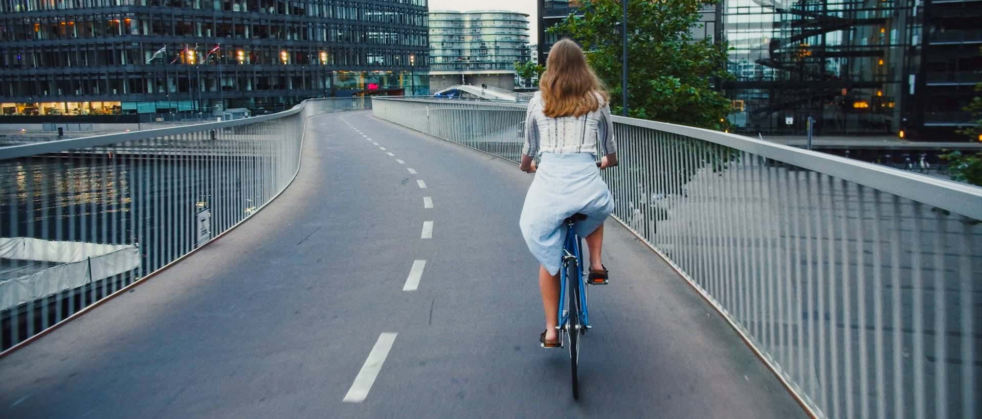 Kvinne sykler rolig ned en vei