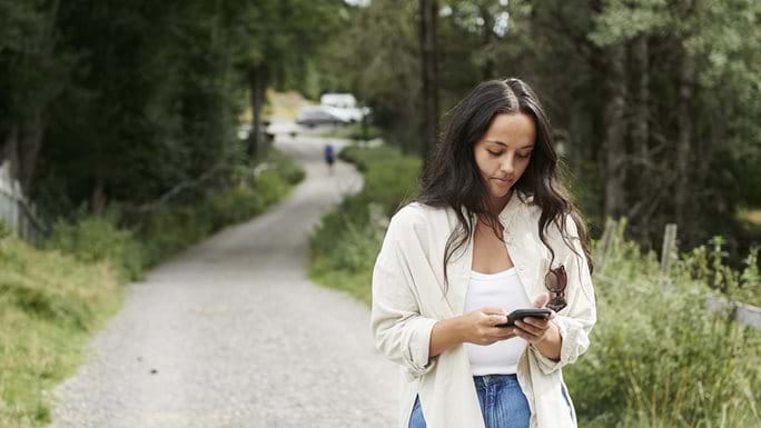 Kvinnelig leder som går igjennom feriesøknader på mobilen i Visma Multi